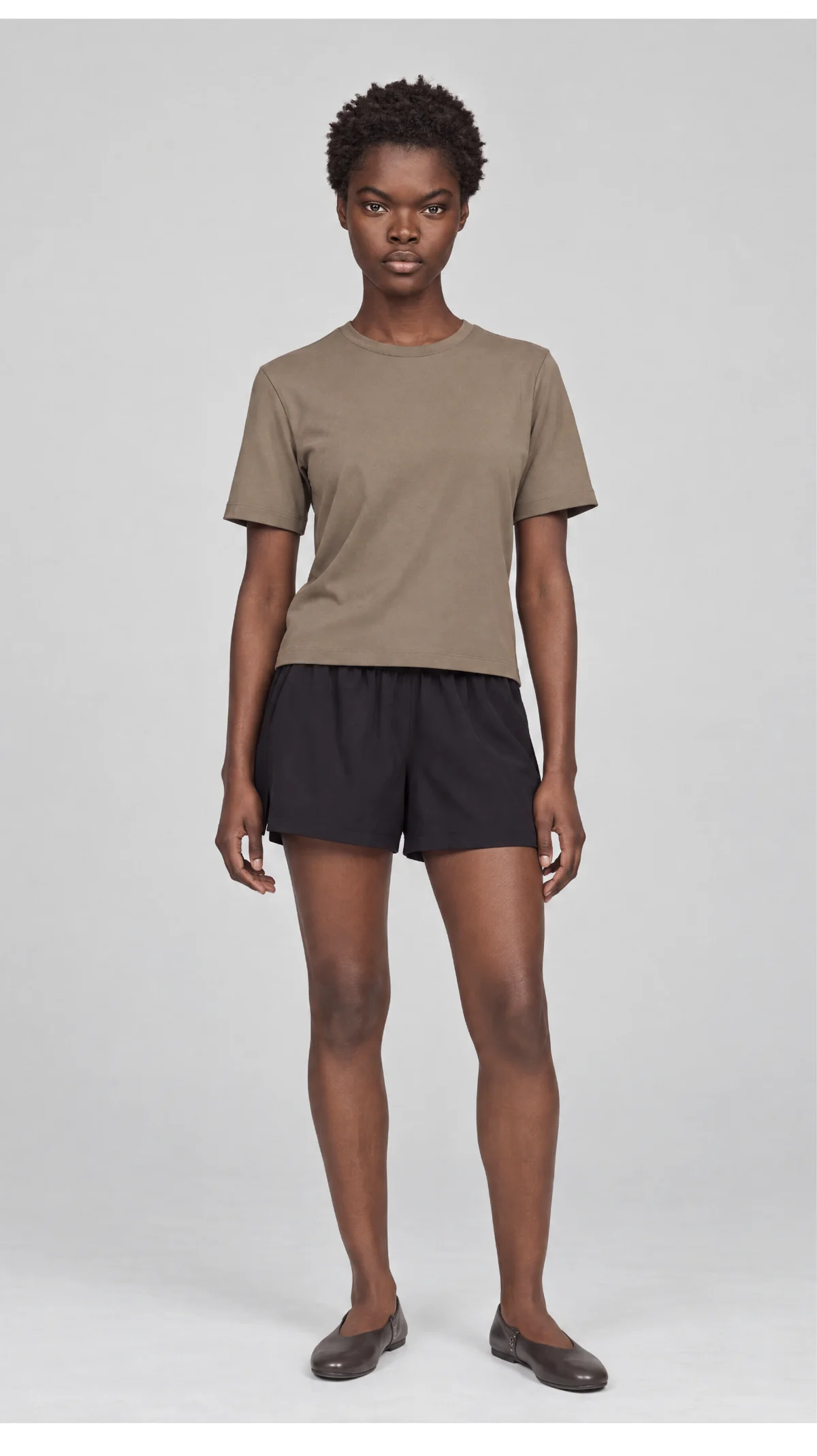 Alternate front catalogue view of a model wearing a taupe T-shirt and black shorts
