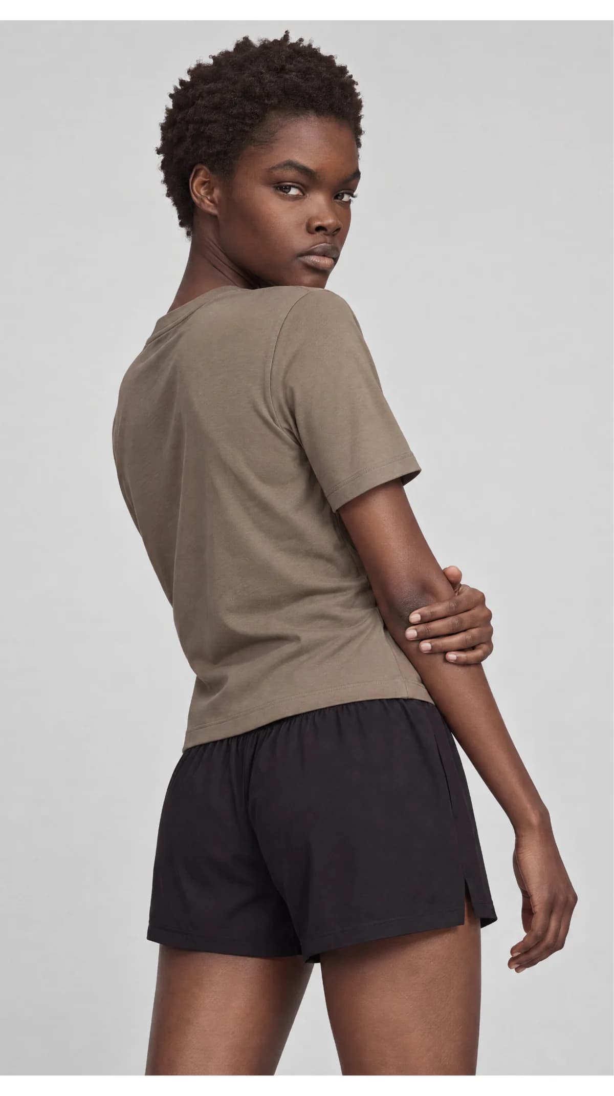 Three-quarter catalogue view of a model wearing a taupe T-shirt and black shorts