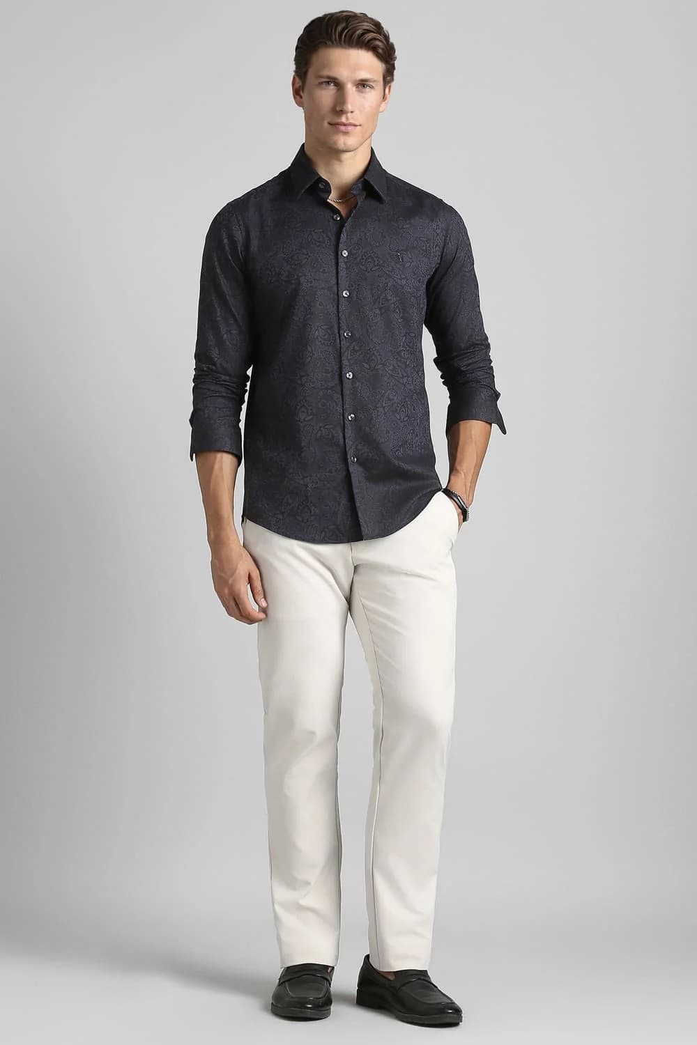 Male fashion model in a blue shirt and dark trousers.