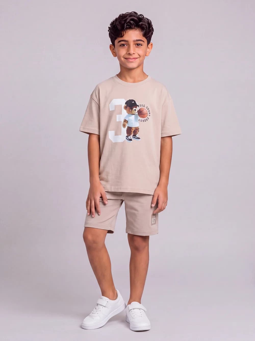 Front-view fashion catalogue image of a child model in a beige outfit.