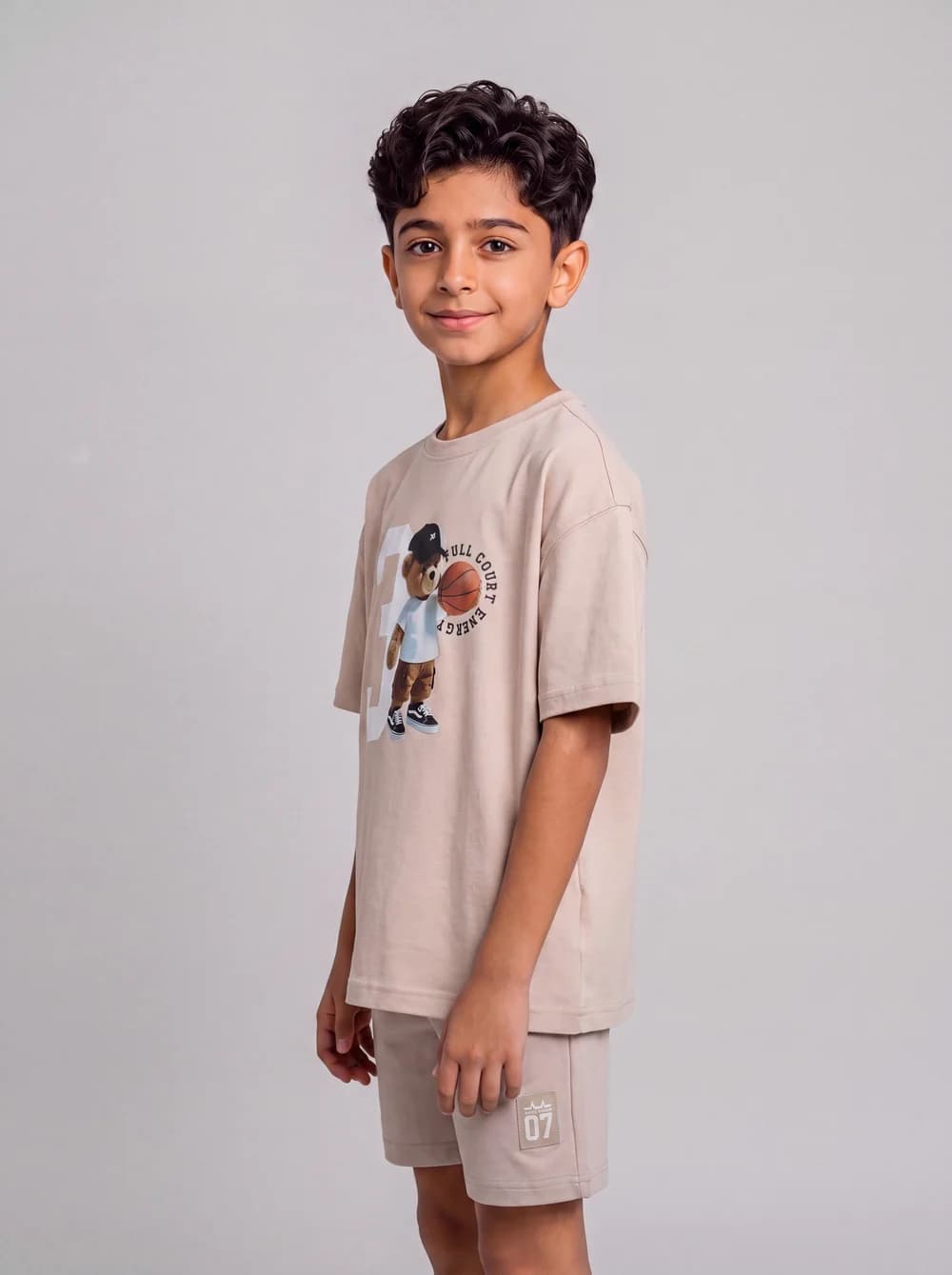 Side-view fashion catalogue image of a child model in a beige outfit.