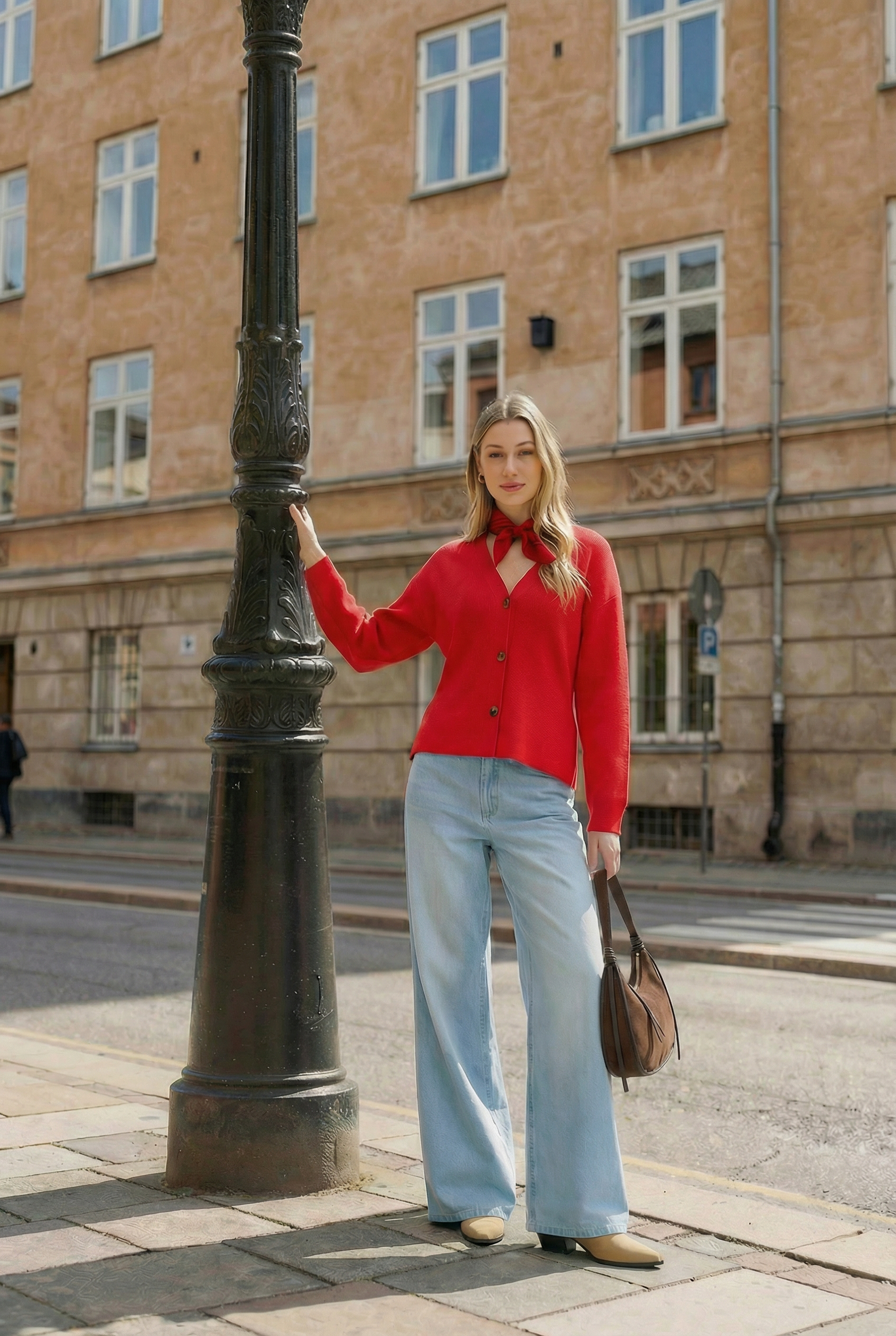 Red fashion campaign portrait beside a black city lamp